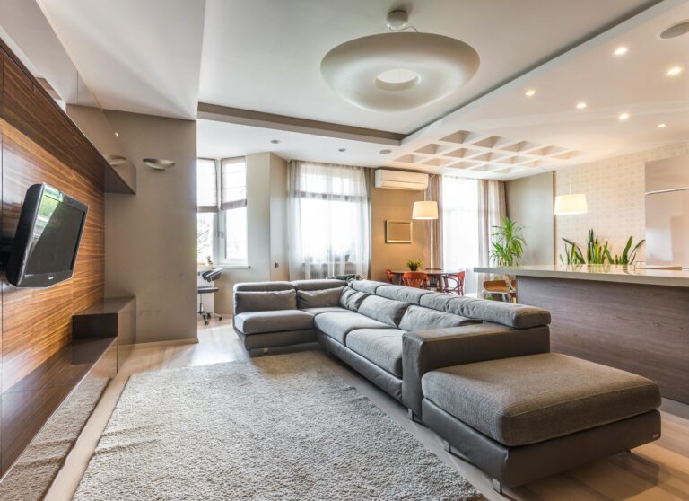 Spacious contemporary living room featuring a sleek grey sectional sofa and open kitchen design.